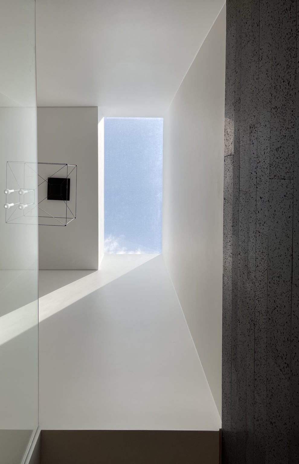Vazio de luz e parede de pedra escura na Casa N